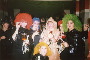 A group of women are in Halloween fancy dress as witches with brightly coloured hair and mummies wrapped in paper