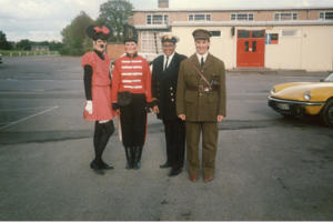 A group of women in fancy dress stand outside a university building. One is Minnie Mouse, one is wearing a red soldier uniform, one is a navy captain and one is dressed as a world war two soldier.