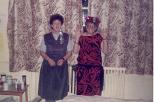 Two women in 1980s party dresses standing against a window