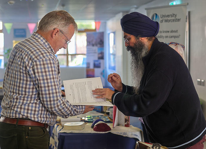 A friendly Sikh man is showing another man a book